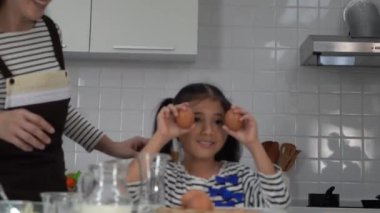 Küçük kız evde annesiyle yemek pişirirken Egg 'le oynuyor..