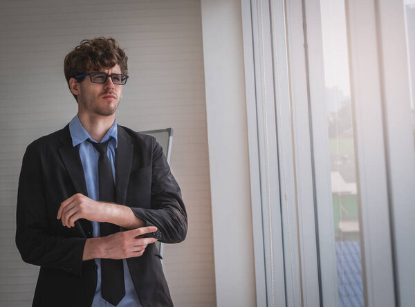 White business with glasses is touching his sleeve getting ready for work.