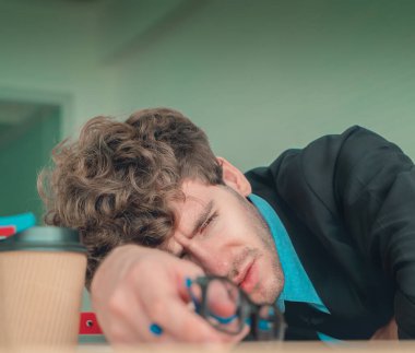 Umutsuz bir iş adamı, bıkkınlık hissi ve bitkin bir yüzle ofis masasında dinleniyor..