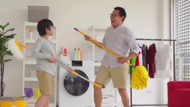 父と息子は家を掃除しながら歌と踊り 家の仕事を一緒にする家族の活動のコンセプト — ストック動画