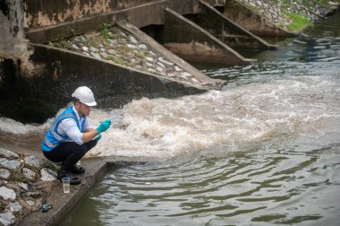 Atık su arıtma işçisi bir kamu kuyusundan su örnekleri topluyor