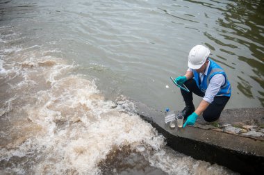 Atık su arıtma işçisi kirleticiler için kamu kanalından su örnekleri topluyor