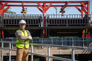 Güneşli alan denetimi sırasında hidrolik su kontrol yapısına güvenle bakan mühendis.