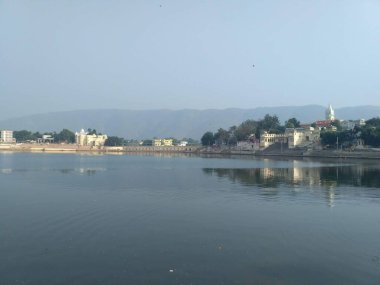 Günbatımı takımında Brahma Sarovar 'ın ghatlarının görüntüsü Pushkar, Rajasthan, Hindistan' da arka planda aravali tepeleri bulunuyor.