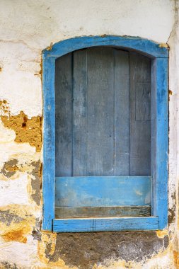Rio de Janeiro eyaletinin güney kıyısındaki tarihi Paraty şehrinde eski ve çürümüş ahşap bir pencere maviyle boyanmış.