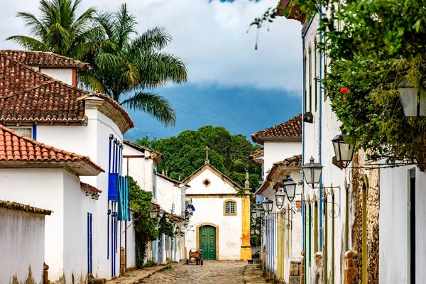 Fenerleri, sömürge tarzı evleri, kaldırımları ve Rio de Janeiro 'nun güney kıyısındaki Paraty' nin arka planında tarihi kilisesi olan eski cadde.