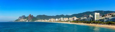 Rio de Janeiro 'daki Ipanema plajının panoramik manzarası etrafındaki binalar ve dağlarla