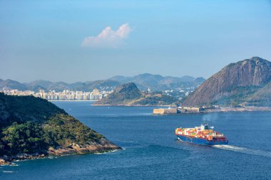 Kargo gemisi Guanabara Körfezi 'ne Rio de Janeiro' nun dağ ve ormanlarından giriyor ve arka planda Niteroi şehri bulunuyor.