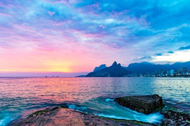 Yaz boyunca Ipanema sahilinde, Rio de Janeiro 'da dağlar ve arka planda şehir ışıkları vardı.