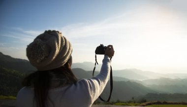 Güneşin altında kahve içen bir kadın güneş ışığında oturmuş sabah kahvesinin tadını çıkarıyor. Yaşam Tarzı Konsepti