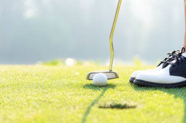 Golfçü Asyalı kadın akşam vakti golf topunu yeşil golf sahasına koyuyor. Sağlıklı ve Yaşam Tarzı Konsepti.