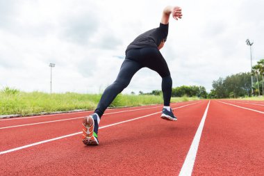 Stadyumdaki koşu bandının başında genç kaslı sporcunun portresi. Rahatlama ve egzersiz konsepti..