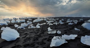 Buz kıran güzel bir manzara, gün batımında dağ sırtı arkaplanı olan donmuş deniz kıyısı.
