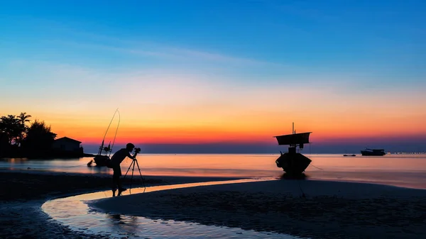 Asia a man nature photographer,Photographer is taking a picture of sunrise at beach with beautiful sky reflection