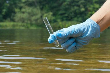 Analiz için nehirden örnek su. El eldiveni tutma 