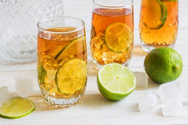 Bir dilim limon ile bir bardak buzlu çay. Beyaz ahşap tahta geri