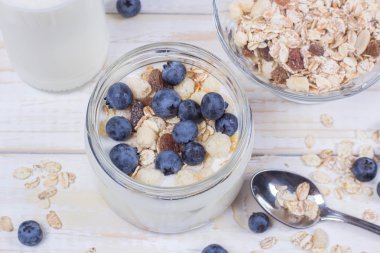 Yaban mersini ve tahıl cam bir kavanoza bir ahşap t ile yoğurt