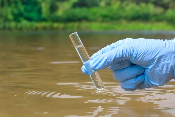 Vzorek vody z řeky pro analýzu. Ruce v rukavičkách — Stock fotografie