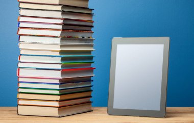 Bir yığın kağıt kitap ve bir e-kitap. Kitapları elektronik ile değiştirme kavramı.