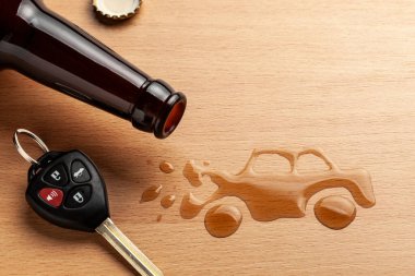 Alkollü araç kullanma. Alkolden dolayı kaza yapmış. Bira şişesi ve araba anahtarları. Bozuk araba.