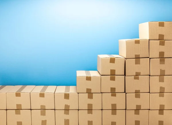 Cardboard boxes steps up for delivery or moving. Stack of boxes and blue background — Stock Photo, Image