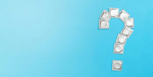 Preservativos en envases en forma de signo de interrogación sobre fondo azul. Copiar espacio para texto. Imagen De Stock