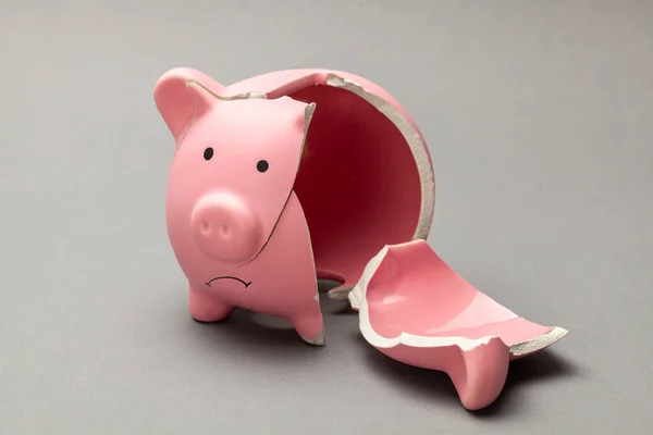 Broken piggy bank on gray background. sad face. — Stock Photo, Image