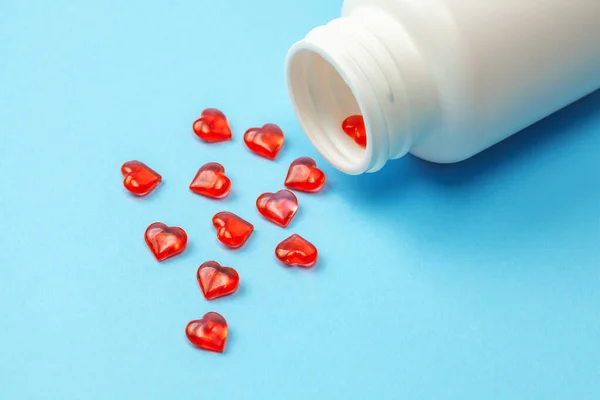 Καρδιολογικά χάπια. Κόκκινα χάπια σε σχήμα καρδιάς με μπουκάλι σε μπλε φόντο — Φωτογραφία Αρχείου