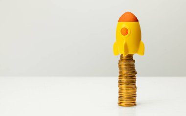 Gri arka planda roket ve altın para yığını