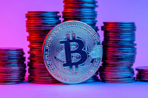 Bitcoin und Stapel von Münzen im Neonlicht — Stockfoto