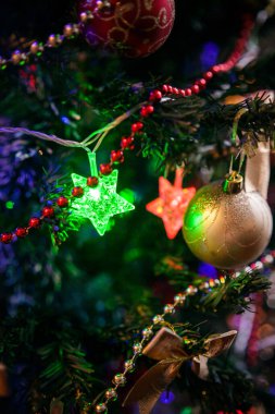 Geleneksel kırmızı ve altın rengi oyuncaklarla süslenmiş Noel ağacı, parlak Noel çelengi