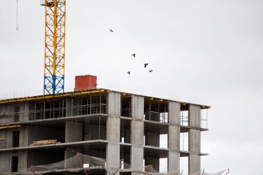 Çok katlı bina gri gökyüzüne karşı yapım aşamasında.