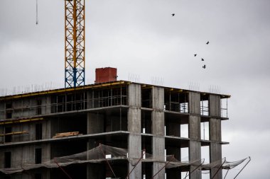Çok katlı bina gri gökyüzüne karşı yapım aşamasında.