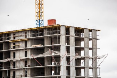 Çok katlı bina gri gökyüzüne karşı yapım aşamasında.