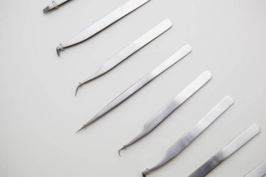 Kirpik uzatma ve kaş tasarımı için araçlar. Beyaz arka planda gümüş renkli kozmetik cımbızlar