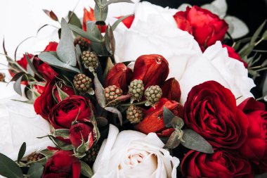 Güzel ve pahalı bir buket kırmızı ve beyaz güller ve okaliptüs yeşillikleri ve ahududu