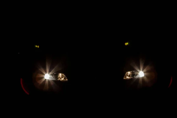 the headlights of an expensive car shine in the dark