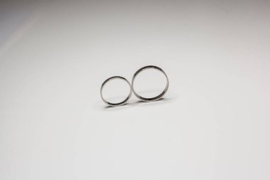 Beyaz arka planda beyaz metalden yapılmış klasik alyanslar.