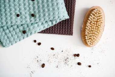 Spa ve rahatlama havluları, kahve çekirdekleri ve anti-selülit fırçalı beyaz arka planda kahverengi ve yeşil havlular.