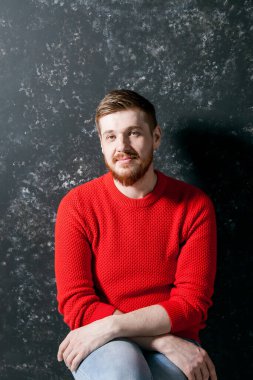 Kızıl saçlı, kırmızı sakallı, genç beyaz bir adam. Kırmızı kazaklı. Elleri olan bir portre.