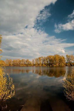 Klasik bahar manzarası, sakin bir gölün su yüzeyine yansıyan ağaçlar.