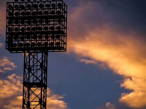 the silhouette of a football field spotlight on the background of an orange and purple sunset