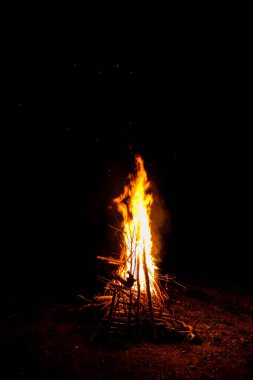 Ormanın karanlığında büyük bir ateş alevleniyor, bir yürüyüş sırasında kamp ateşi yakıyor.