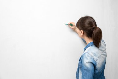 Genç kadında rahat kıyafetler ile çizim veya boş duvara yazı kalem arkası