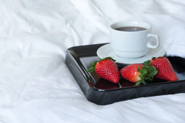 Petit déjeuner de fraises et une tasse de café sur un plateau noir — Photo