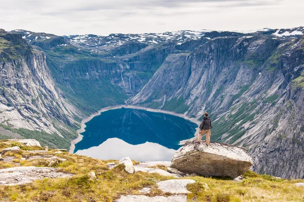 Adam üstte duruyor ve dağ gölü görünüyor. Norveç