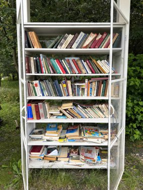 Moskova, Rusya. 22 Ağustos 2025. Açık hava halk kütüphanesi bir parkta, cam bir dolabın içindeki raflarda kitaplar, halk okuması.