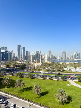 Sharjah, BAE- 8 Kasım 2025. Al Majaz Rıhtımı yeşilliği modern kulelerle harmanlıyor, yeşillik şekilleri serinletici kamusal alanları manzaralı çimlerle, palmiyelerle ve doğal tonlarla günlük şehir yaşamını geliştiriyor.