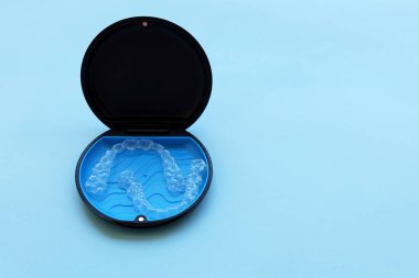 Şeffaf ortodontik hizalayıcılar koruyucu durumda dinleniyor, temiz tasarım ve uygun günlük kullanım. Diş sağlığı klinikleri, markalar ve diş düzeltme konusunda eğitici içerik için mükemmel.