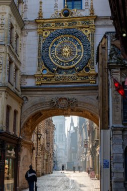 Rouen, Fransa - 27 Mart 2025. Sabahın erken saatlerinde Rouen 'de Le Gros Horloge görünür bir şekilde, yumuşak güneş ışığı cephelerini aydınlatıyor, sokaklar boş, sakin tarihi şehir atmosferi yaratıyor.